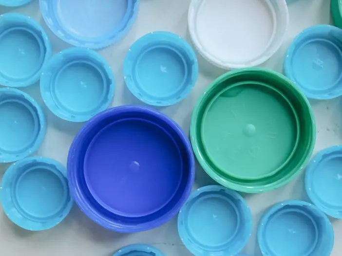 Bottle caps in shades of blue are on a table.