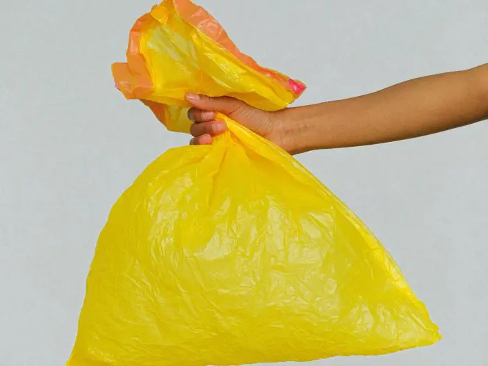 5 Recycling Myths. A yellow garbage bag is being held.