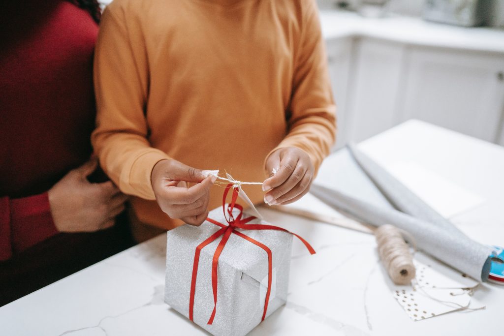 A young child is wrapping a Christmas gift. The photo is to illustrate the idea of recycling Christmas waste.