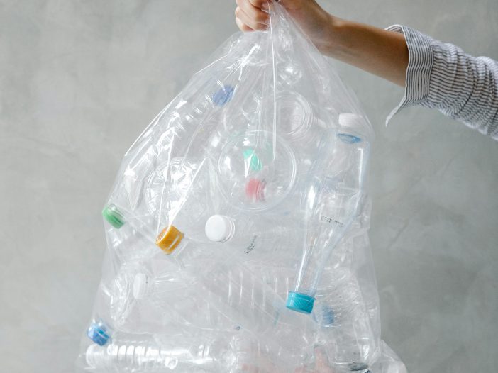 How Can We Reduce The Cost Of Waste Disposal? A clear plastic bag of waste is being held up.